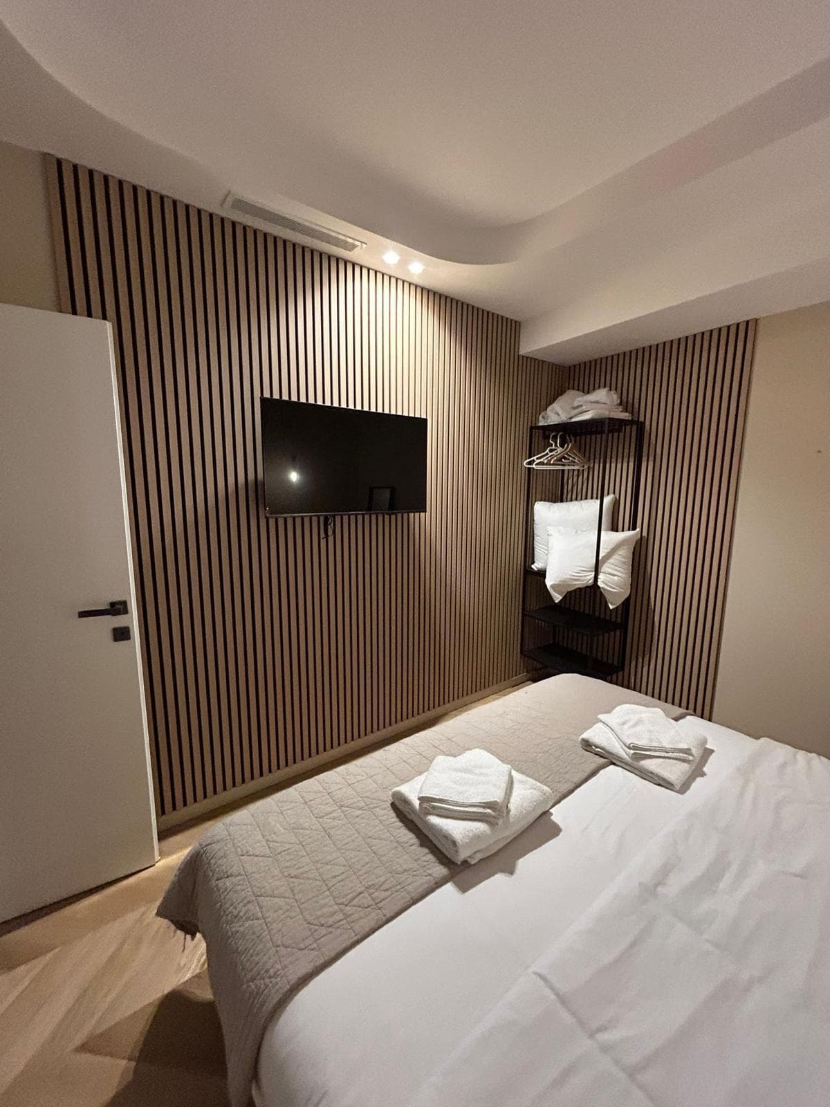 Chambre avec mur habillé de tasseaux de bois et faux plafond à éclairage indirect