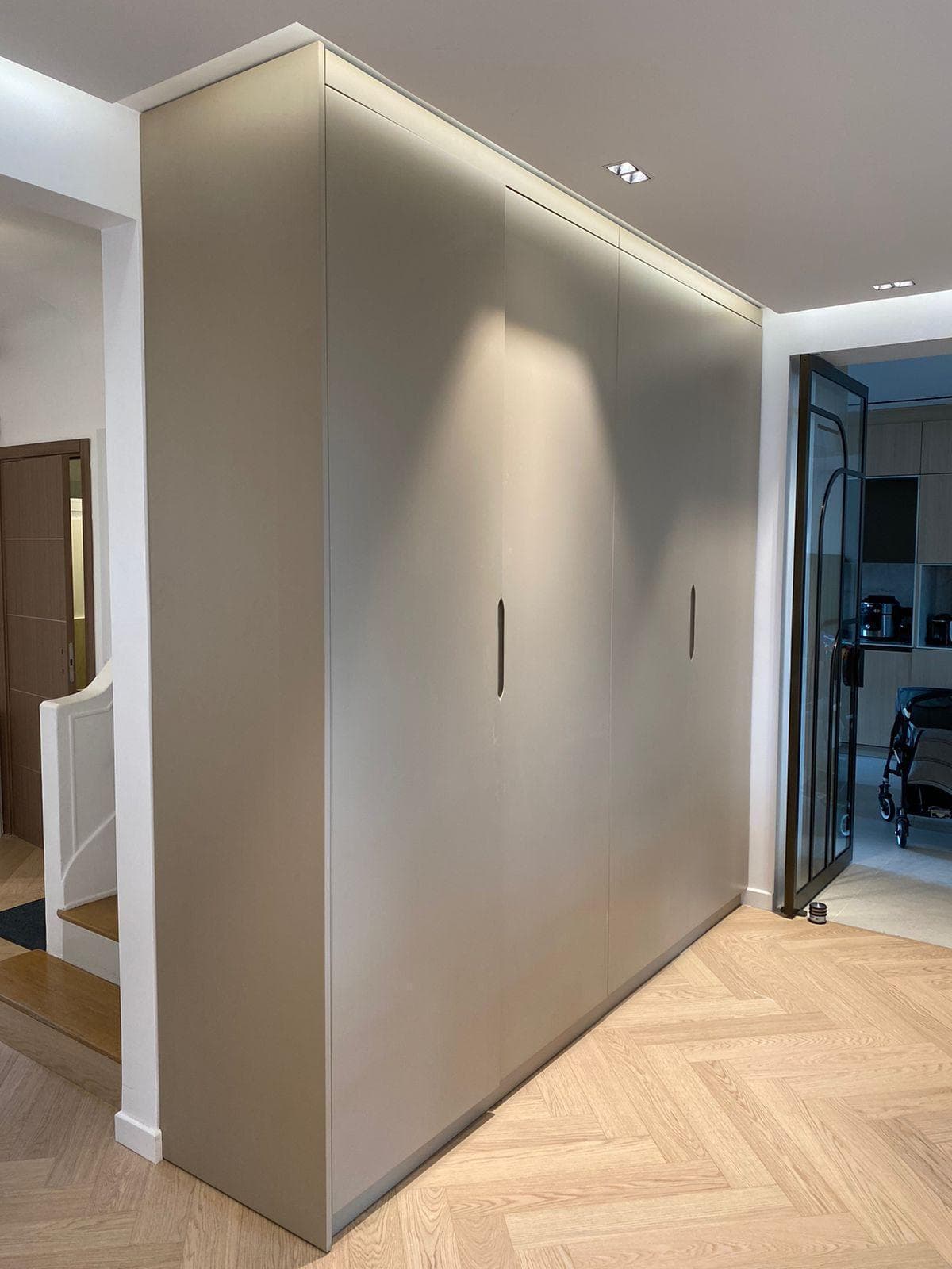 Dressing d’entrée toute hauteur aux façades beiges, parquet en chevron