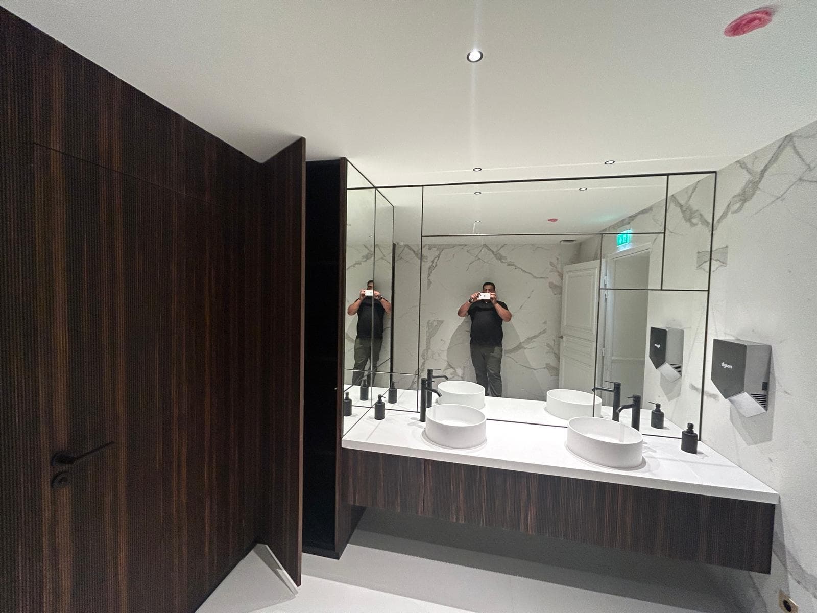 Salle de bain à double vasque, meuble suspendu en bois et murs effet marbre