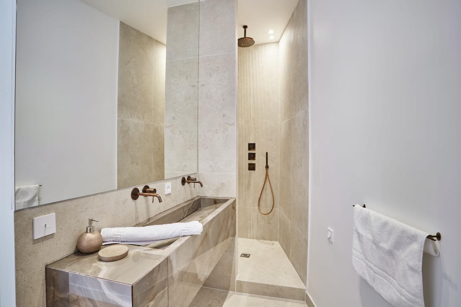 Salle de bain en travertin, douche à l’italienne et robinetterie cuivrée