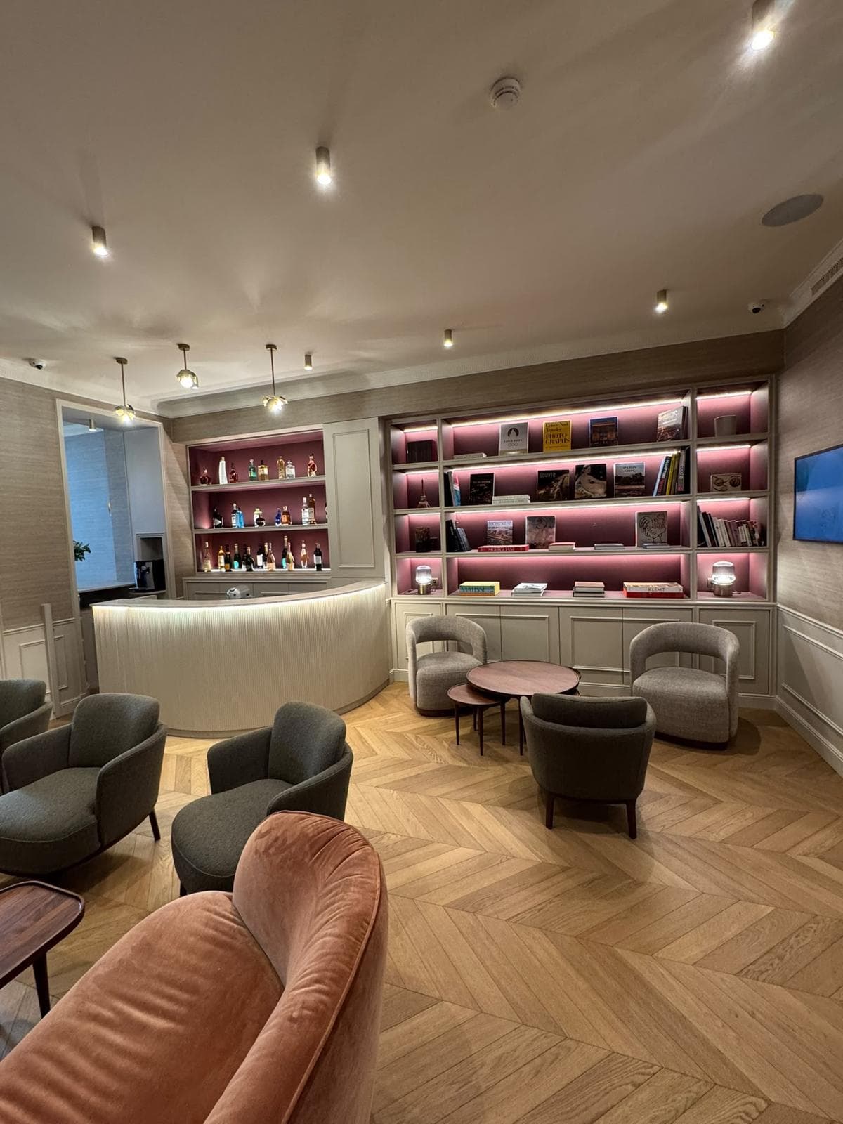 Salon avec bibliothèques rétroéclairées, comptoir arrondi et parquet en chevron