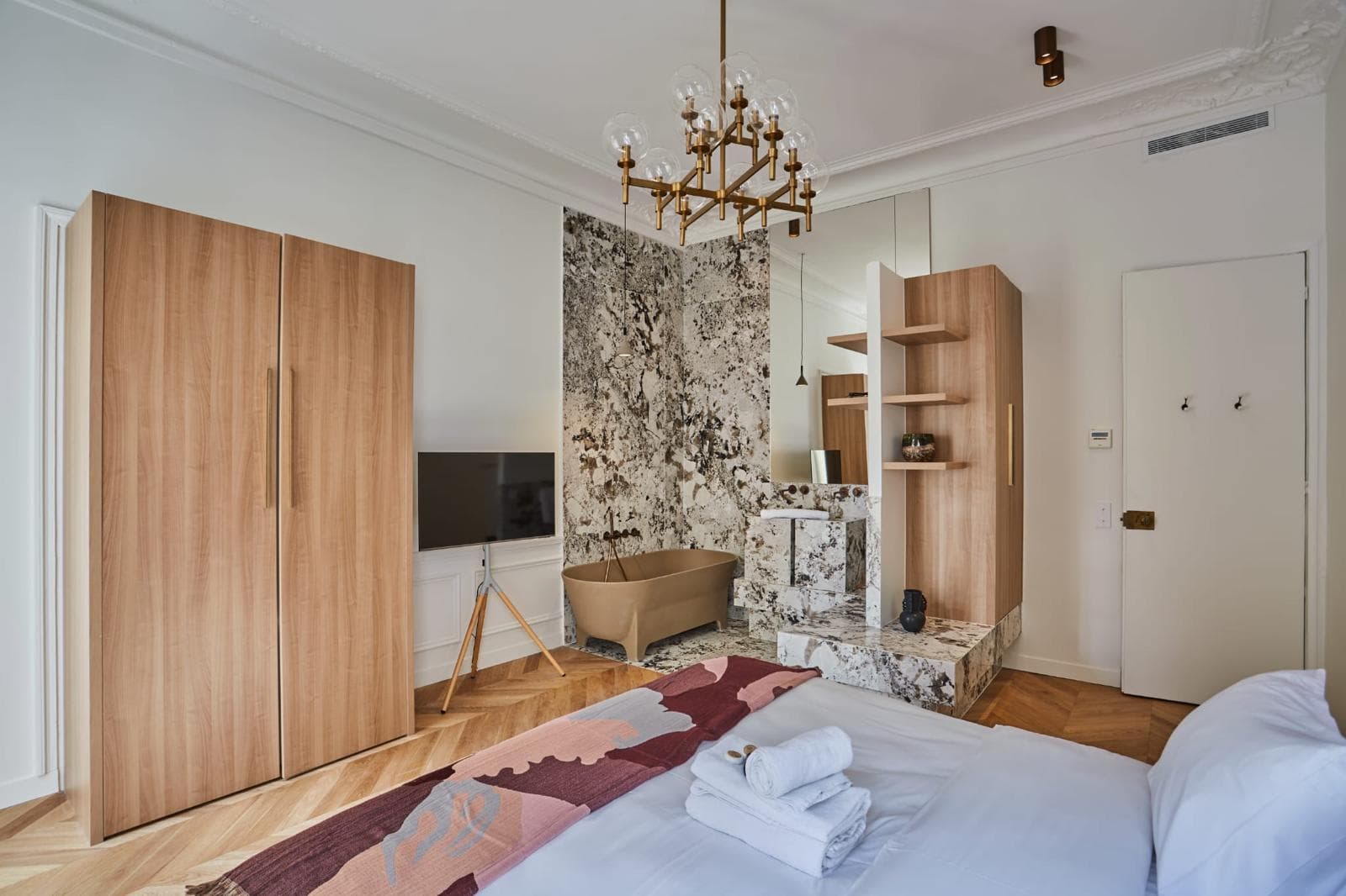 Suite parentale avec armoire en bois toute hauteur et salle de bain ouverte en pierre